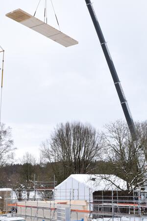 Das rund 8 Tonnen schwere Wandelement wird mit einem großen Kran auf das Baufeld gehoben. <br> © Bezirk Oberbayern, Archiv BHM Amerang