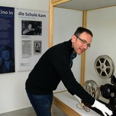 Kurator Niklas Hertwig positioniert den historischen 35mm-Handkurbel-Projektor Bing Optica aus den 1920er Jahren.<br>  Bezirk Oberbayern, Archiv BHM Amerang