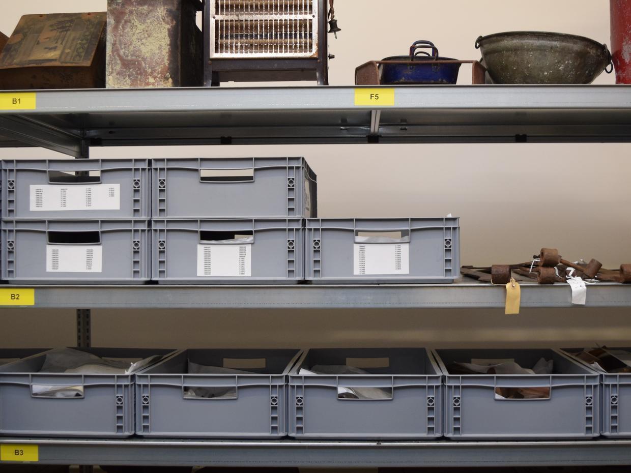 Die Metallobjekte des Museums liegen eingepackt in grauen Kisten im Depot. Auf den Stirnseiten der Boxen sind die Inventarnummern zu lesen. <br> © Bezirk Oberbayern, Archiv BHM Amerang